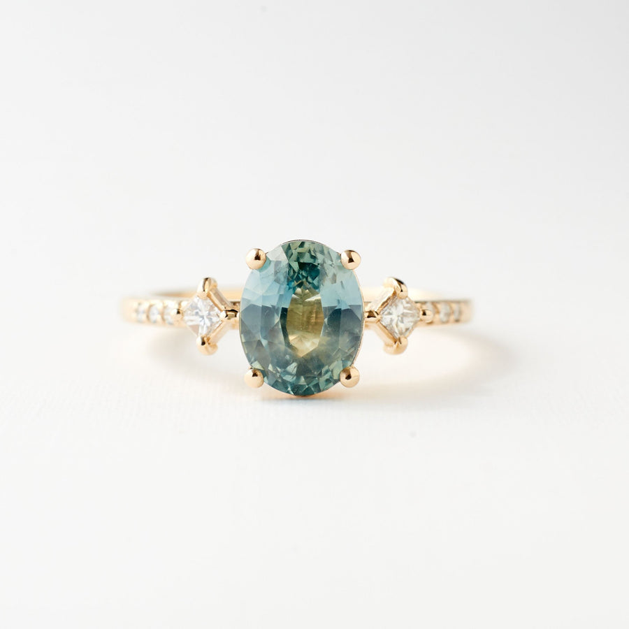 May ring set with a light blue-green oval sapphire. 